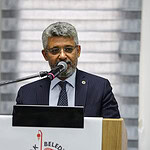 Nüfus müdürü, belediye toplantısında konuşma yaparken mikrofon kullanıyor.