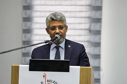 Nüfus müdürü, belediye toplantısında konuşma yaparken mikrofon kullanıyor.