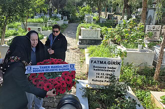 Anma töreninde yaşlı kadınlar ve belediye başkanı mezar ziyaretinde, sevgi ve saygı gösteriyor.