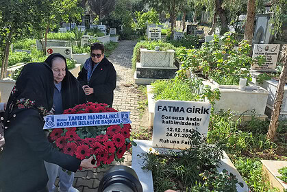 Anma töreninde yaşlı kadınlar ve belediye başkanı mezar ziyaretinde, sevgi ve saygı gösteriyor.