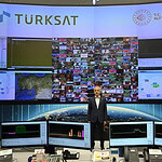 Türkiye Ulaştırma Bakanlığı ve Türksat logosu ile haber merkezi ekranları.