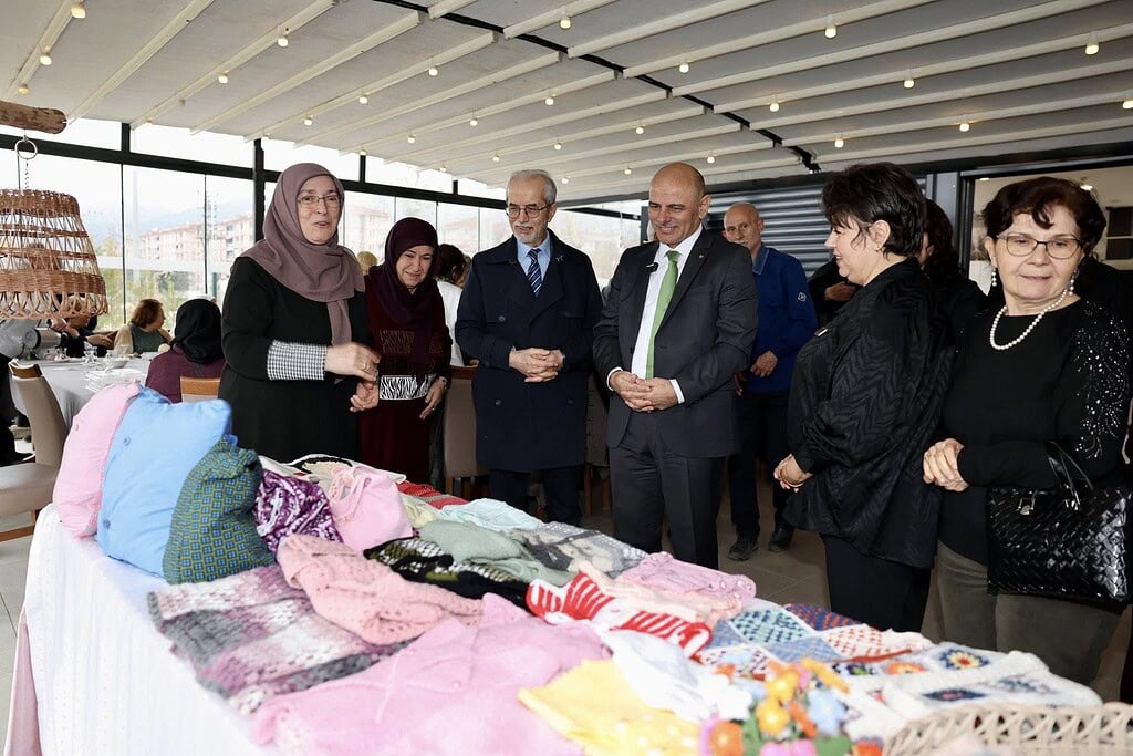 Körfez 60+ Merkezi geri dönüşüm ve el sanatları sergisi, yaşlılar ve ziyaretçilerle dolu, renkli el.